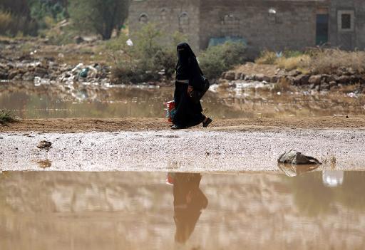 Một phụ nữ Yemen đi qua vũng nước sau khi lũ lụt vây quanh thủ đô Sanaa