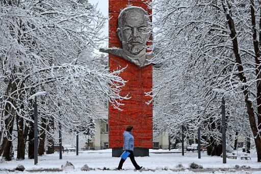Một phụ nữ đi trước một tượng đài vinh danh người sáng lập Liên bang Xô viết, Vladimir Lenin ở Moscow