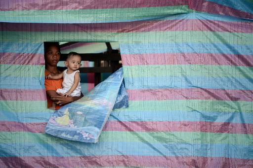 Một đứa trẻ giữ em trai trong lều viện trợ nhân đạo ở thành phố Tacloban (miền trung Philippines) sau khi bị tàn phá bởi cơn bão Haiyan