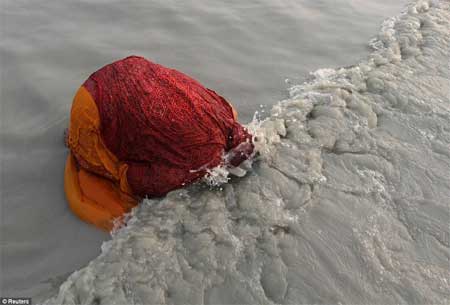 Một người hành hương theo đạo Hindu nhúng mình xuống sông Hằng hôm 14/1.