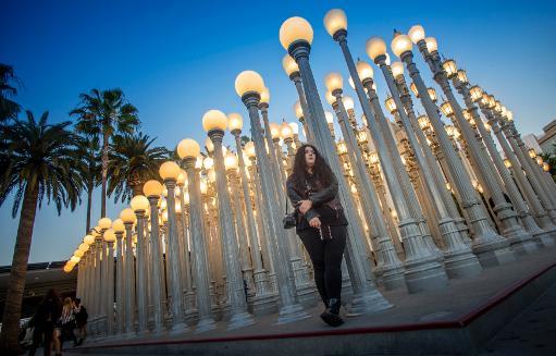 Một phụ nữ trẻ trước cụm đèn đô thị ở  phía trước của Bảo tàng Nghệ thuật Los Angeles. Cụm đèn được thiết kế từ những bóng đèn cũ để kêu gọi tiết kiệm điện