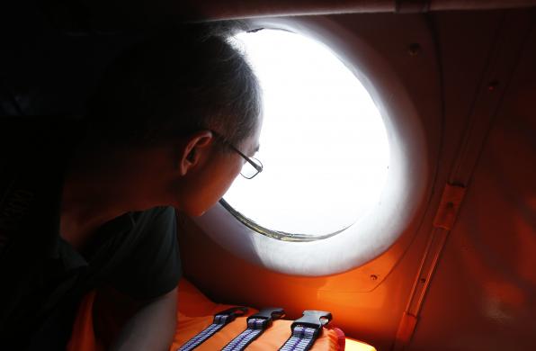 Một nhà báo nhìn qua cửa kính máy bay Việt Nam trong một chuyến bay tìm kiếm