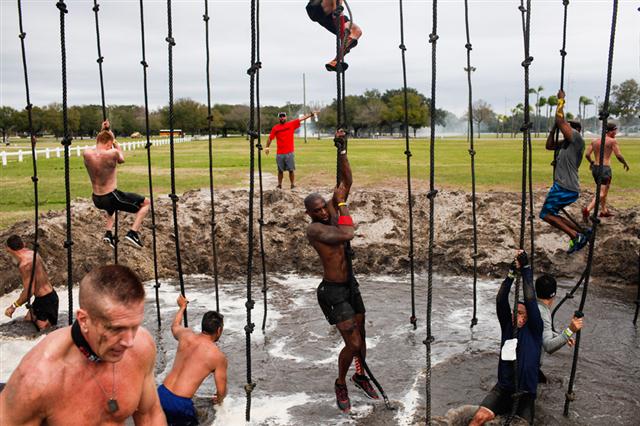 Những người tham dự cuộc thi leo lên và tuột xuống một chiếc dây thừng ở một hố bùn trong sự kiện ở Florida