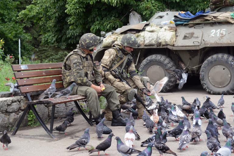 Binh sĩ Ukraina cho chim bồ câu ăn ngay bên cạnh xe thiết giáp của họ, ảnh chụp gần tòa thị chính ở thành phố miền đông Ukraina của Slavyansk