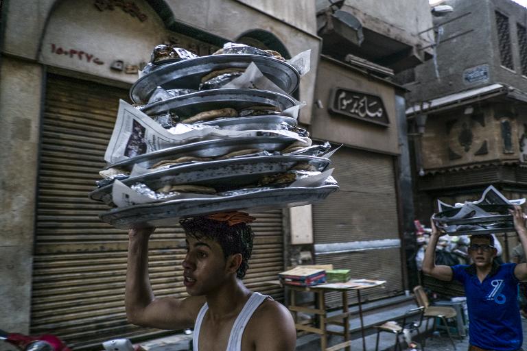 Hai người đàn ông Ai Cập mang những chiếc bánh để phục vụ khách hàng trong tháng thánh lễ Ramadan trong huyện Cairo khan el-Khalili, Ai Cập