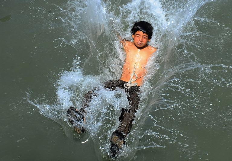 Một cậu bé Afghanistan lao mình xuống nước để tránh nắng nóng trong một con kênh ở Herat, thành phố lớn thứ 3 của Afghanistan