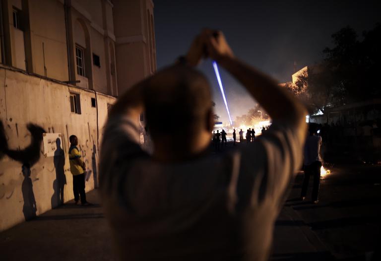 Một người biểu tình Bahrain cầm đèn laser chiếu vào đám đông trong một cuộc biểu tình chống lại nhà cầm quyền tại làng Sanabis, phía tây của thủ đô Manama