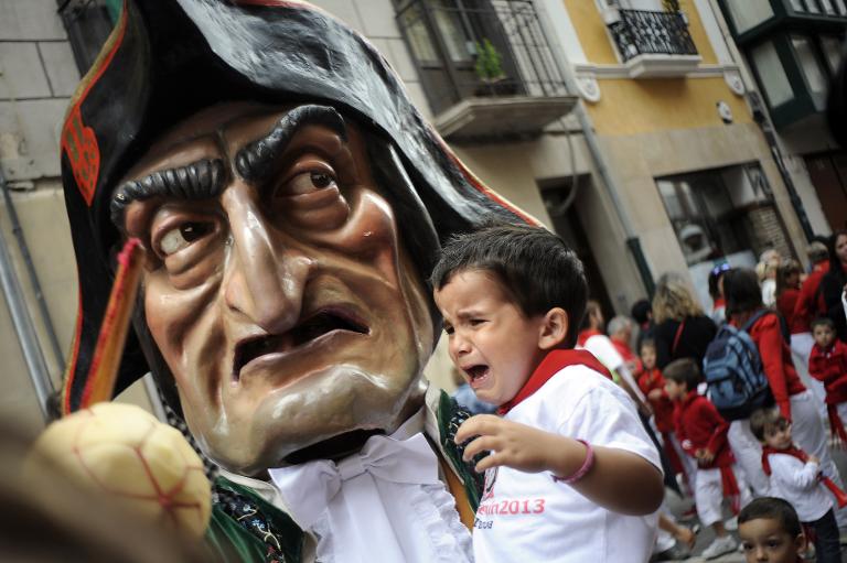 Một đứa trẻ khóc lóc sợ hãi khi được một người hóa trang bế trên tay tại lễ hội San Fermin ở Pamplona, ​​miền bắc Tây Ban Nha