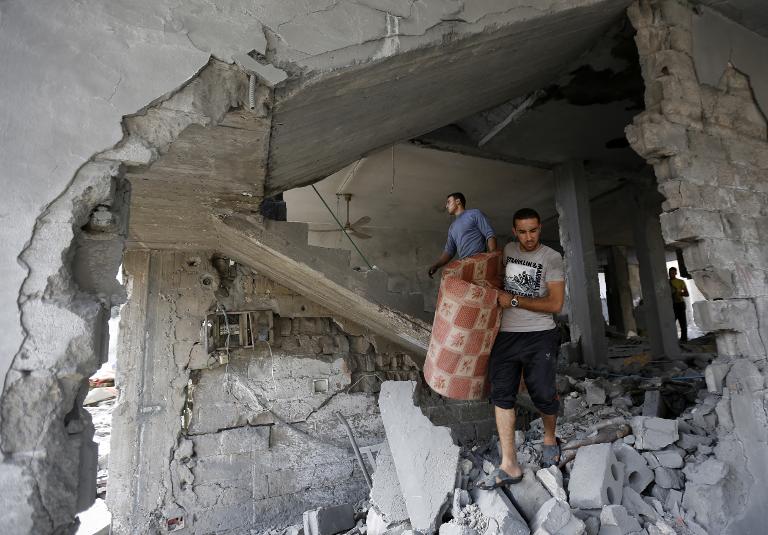 Người dân Palestine dọn dẹp đống đổ nát của một tòa nhà bị phá hủy sau cuộc không kích của Israel vào buổi sáng tại thành phố Gaza