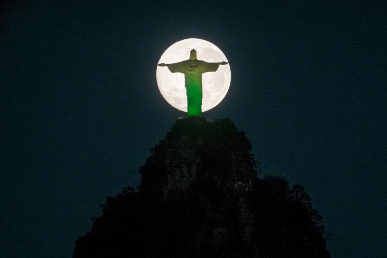 Mặt trăng xuống phía sau bức tượng của Chúa Kitô Đấng Cứu Thế trên đỉnh đồi Corcovado ở Rio de Janeiro, Brazil