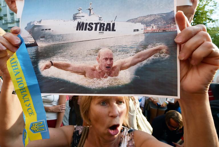 Một người biểu tình giơ cao tấm ảnh Tổng thống Nga Vladimir Putin bơi ở phía trước của một tàu chiến lớp Mistral, trong một cuộc biểu tình trước nơi văn phòng đại sứ Pháp tại Kiev
