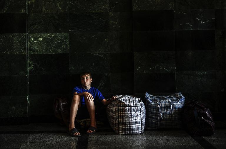Một cậu bé ngồi cạnh hành lý của mình trong khi chờ đợi đoàn tàu tại một nhà ga ở trung tâm thành phố Donetsk, phía đông Ukraine