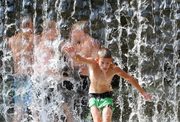 Một cậu bé lao mình vào thác nước trong công viên ở thành phố Vilnius vào một trong những ngày nóng nhất của mùa hè này ở Litva