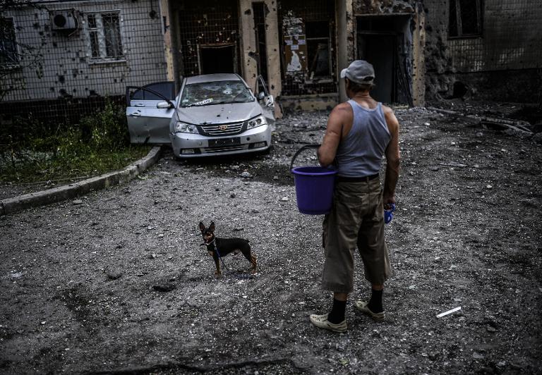 Một người đàn ông đứng yên lặng nhìn vào ngôi nhà bị hư hỏng nặng sau đợt bắn phá gần đây nhất tại Donetsk