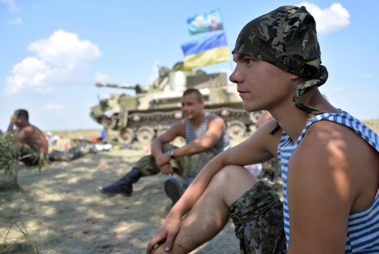 Binh sĩ Ukraina ngồi nghỉ trong bóng râm bên cạnh một chiếc xe tăng khi họ dừng chân ở một vị trí gần thành phố phía đông của Debaltceve, trong khu vực Donetsk