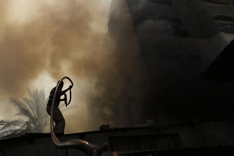 Một người đàn ông Palestine cố gắng dập tắt ngọn lửa đang thiêu rụi ngôi nhà ở thành phố Gaza
