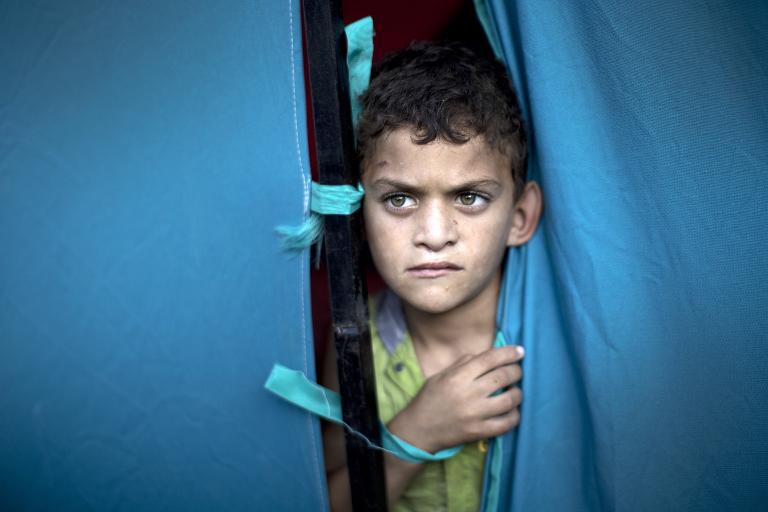 Một cậu bé Palestine nhìn từ căn lều tạm dành cho những người di tản tránh bạo lực tại khuôn viên bệnh viện al-Shifa ở thành phố Gaza