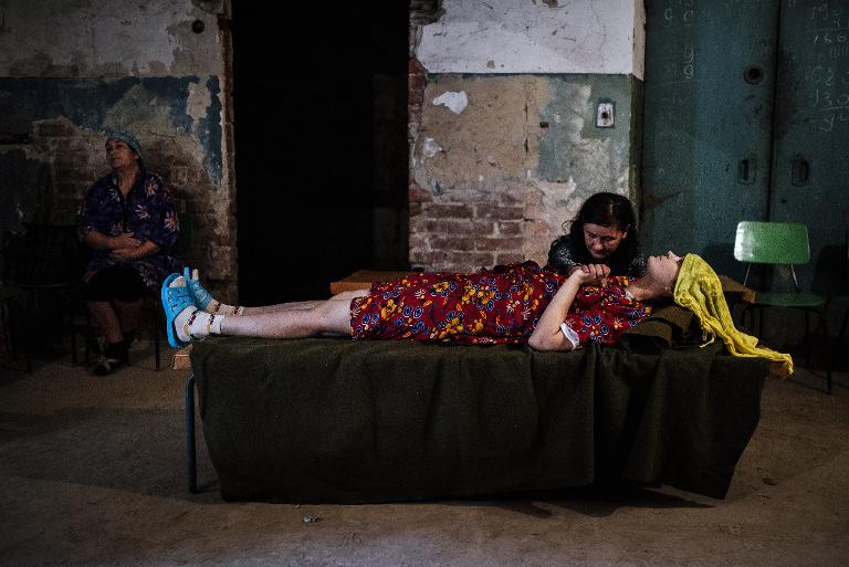 Một người phụ nữ nắm tay đứa con gái đang bị bệnh của mình trong tầng hầm trú bom của bệnh viện Kalinina, Donetsk