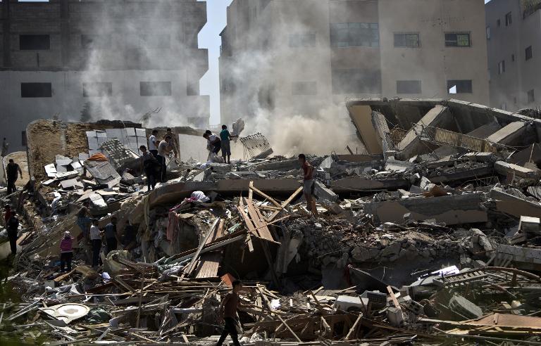 Người dân Palestin đứng trên đống đổ nát của tòa nhà 12 tầng sụp đổ vì các cuộc không kích của Israel vào thành phố Gaza