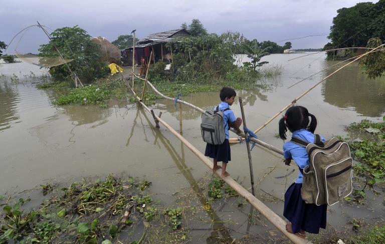 Học sinh Ấn Độ sử dụng một cây cầu tre để vượt qua nước lũ ở làng Morkata, quận Morigoan Assam, bang Assam, Ấn Độ