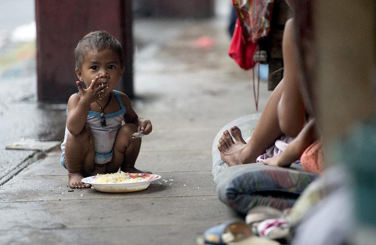 Một đứa trẻ vô gia cư ăn dĩa cơm ngay trên vỉa hè trong một khu ổ chuột tại thủ đô Manila, Philippines