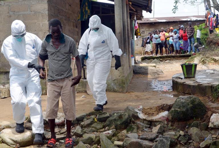 Một gia đình Liberia đứng từ xa nhìn theo người đàn ông nhiễm Ebola đang được các bác sỹ đưa tới bệnh viện ở Monrovia, thủ đô Liberia