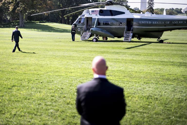 Tổng thống Mỹ Barack Obama bước trên bãi cỏ phía Nam của Nhà Trắng, tiến về phía trực thăng dưới sự giám sát bảo vệ của lực lượng an ninh