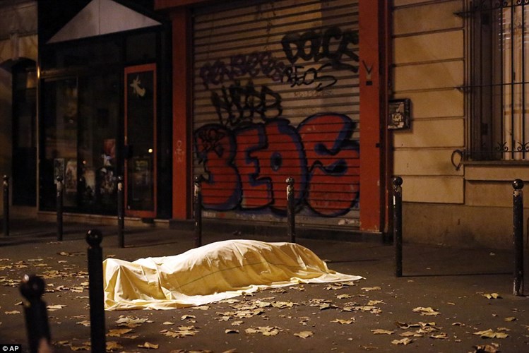 Một nạn nhân thiệt mạng được che phủ tạm thời bằng tấm chăn bên ngoài nhà hát sau vụ thảm sát. (ảnh: AP).
