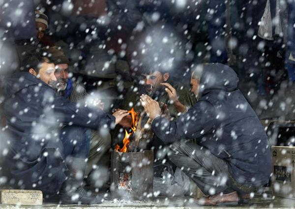 Người dân Kashmir sưởi ấm bên lò lửa khi ngoài trời tuyết đang rơi, ở Tangmarg, phía Bắc Srinagar, 11/02/2016.