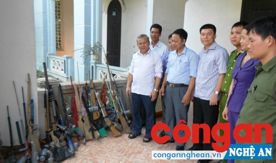  Linh mục Phan Văn Thắng (bên trái) bàn giao súng tự chế và dao, kiếm vận động thu hồi được cho Công an huyện Nghi Lộc