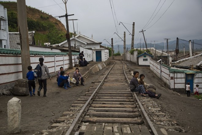 Hình ảnh người dân ngồi nghỉ bên cạnh một đường ray tàu hỏa chạy qua thị trấn nhỏ ở tỉnh Bắc Hamgyong, Triều Tiên qua góc máy phóng viên AP cho thấy cuộc sống tương đối lạc hậu ở những khu vực xa xôi của Triều Tiên.