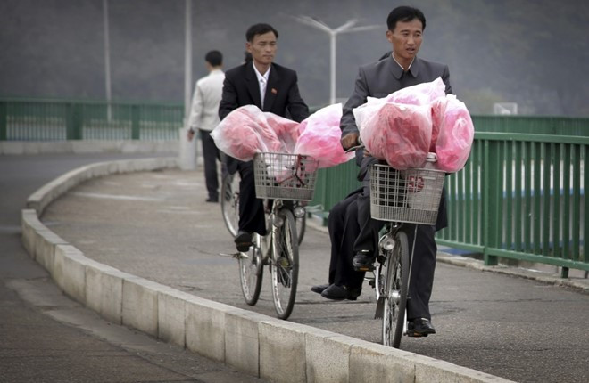 Người dân đi xe đạp, chở những bó hoa được dùng cho lễ kỷ niệm sắp diễn ra tại thủ đô.
