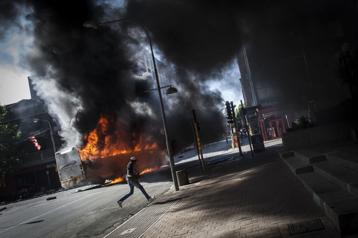 Một chiếc xe buýt bị đốt cháy trong cuộc biểu tình tai quận Braamfontein, thành phố Johannesburg, Nam Phi. Ảnh: AFP