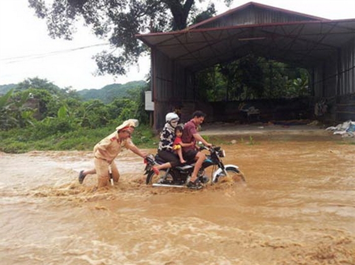 Hình ảnh 2 CSGT tại huyện Mai Sơn (tỉnh Sơn La) không nề hà dòng nước chảy xiết để đẩy xe giúp người dân vượt qua đoạn đường nguy hiểm đã chiếm được cảm tình của đông đảo người dân.