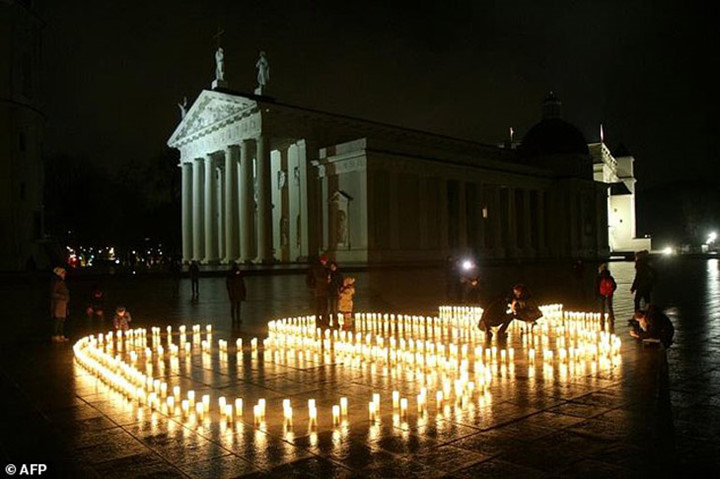 Người dân thắp những ngọn nến trong sự kiện tắt đèn hưởng ứng giờ Trái đất bên ngoài Nhà thờ Vilnius ở Lithuania. (Ảnh: AFP)