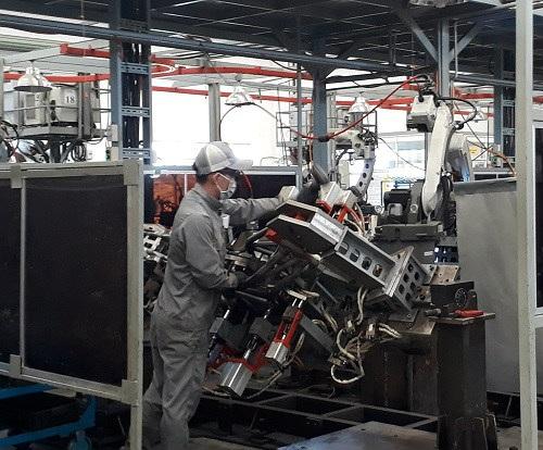 Công nhân Công ty VPIC thực hiện ráp phần khung sườn chiếc xe máy Ducati lên khuôn, các việc còn lại sẽ do robot thực hiện. Mỗi công nhân sẽ phụ trách 2 robot. Ảnh: Hà Thế An.