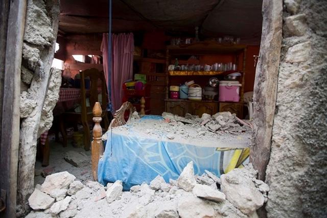 Một chiếc giường phủ đầy các mảnh gạch đá vỡ rơi xuống trong một căn nhà ở Haiti sau trận động đất. Ảnh: AP 