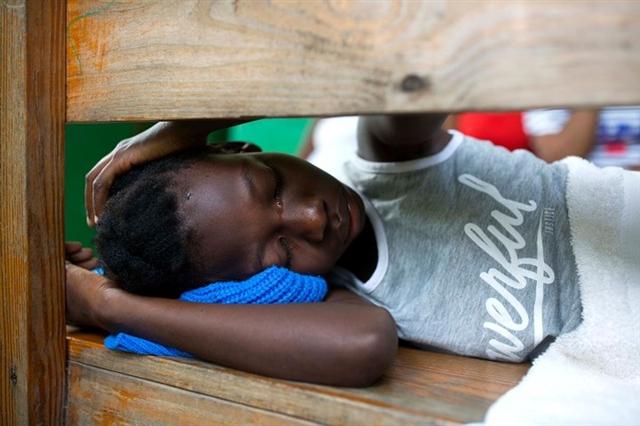 Cô bé Wisberline Normil 12 tuổi vừa chạy thoát khỏi trận động đất, nằm mệt mỏi trong một bệnh viện ở Gros Morne, Haiti ngày 7/10. Ảnh: AP
