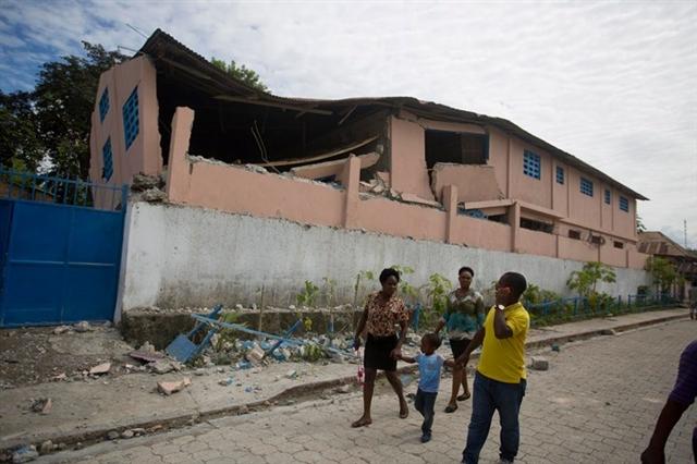 Những người dân đi qua một ngôi trường bị trận động đất tàn phá. Ảnh: AP 