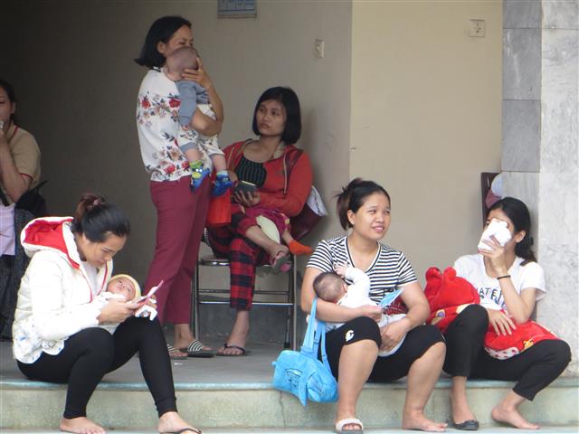 Nhiều bà mẹ phải đưa con trẻ ngồi chờ ở hành lang Trung tâm y tế, chờ đến lượt gọi tiêm phòng