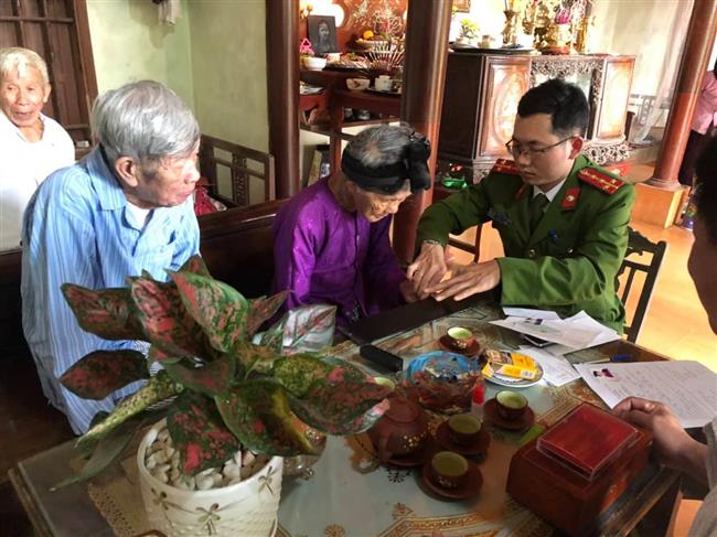 Cán bộ Công an huyện Quỳnh Lưu làm thủ tục lăn tay cho cụ bà Hồ Thị Sửu
