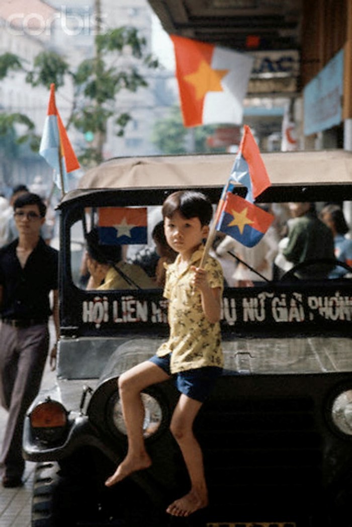 Bé trai ngồi trên xe jeep, tay cầm lá cờ vẫy chào các lực lượng giải phóng tiến vào Sài Gòn ngày 30/4/1975. (Ảnh: Jacques Pavlovsky/Sygma/CORBIS)
