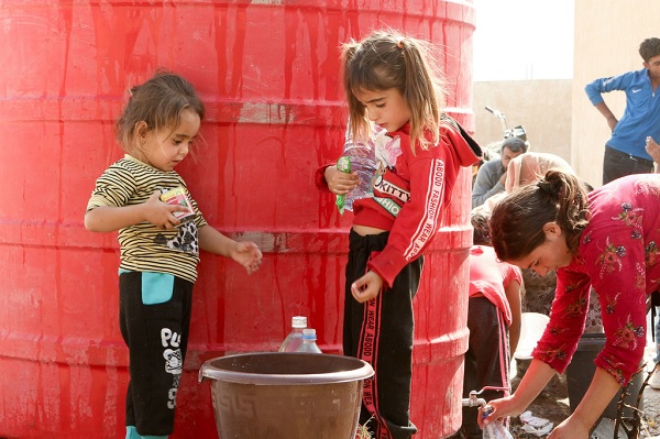 Hai em bé đang chờ để lấy nước do UNICEF mang đến Tall Tamr ở Đông Bắc Syria. (Ảnh: UNICEF)